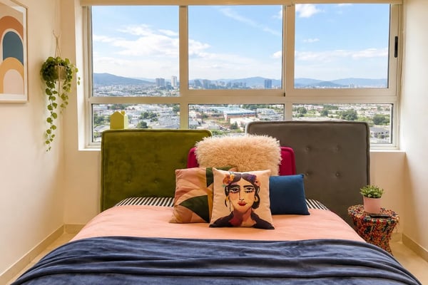 Estudio moderno con mesa de comedor, sofá, asiento junto a la ventana y vista al horizonte de la ciudad a través de grandes ventanas